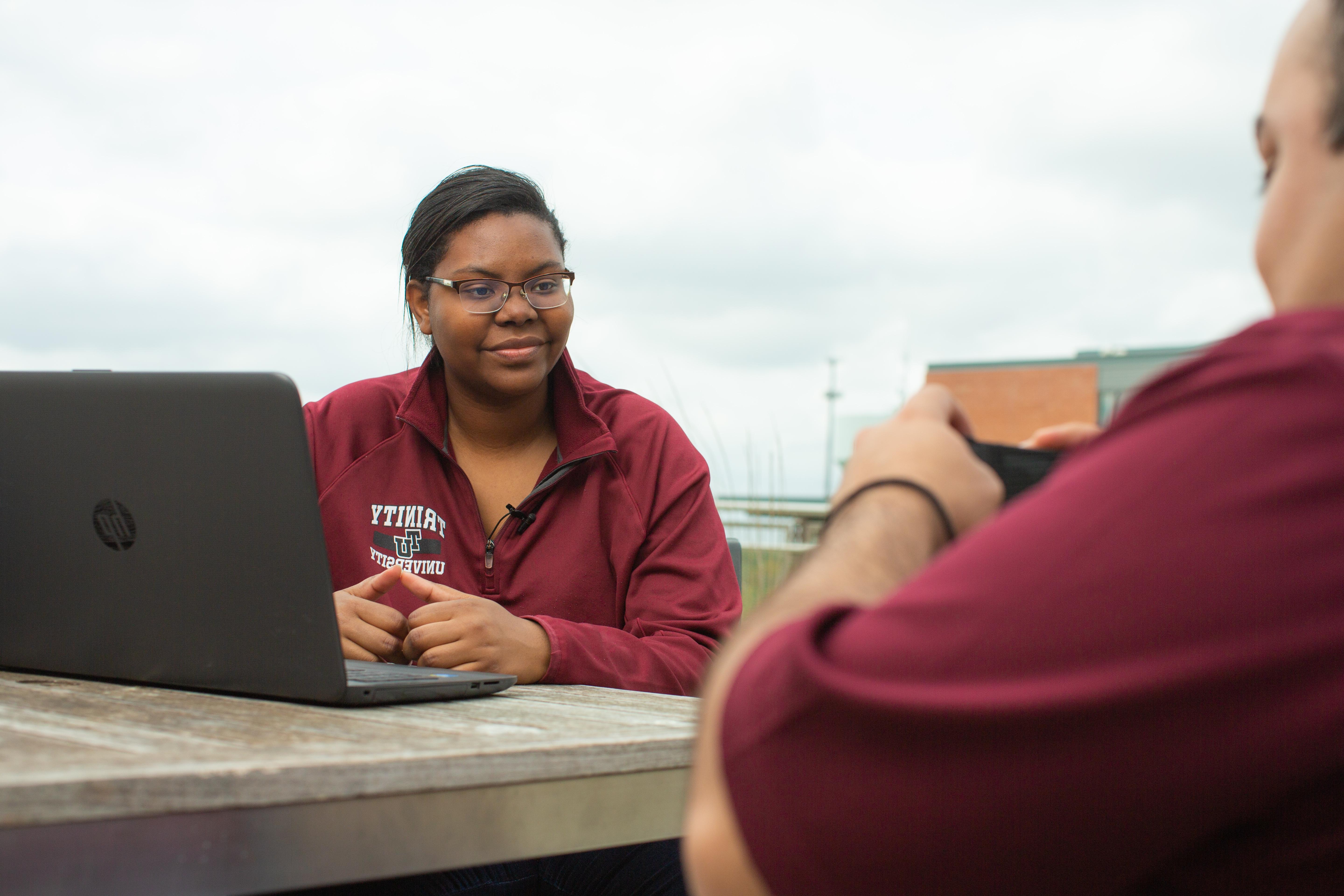 学生们坐在外面用笔记本电脑聊天和工作的照片