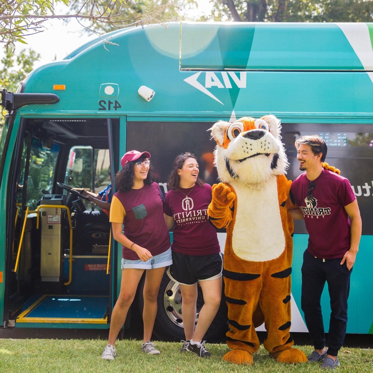 three students and the LeeRoy mascot stand in front of the VIVA culture bus
